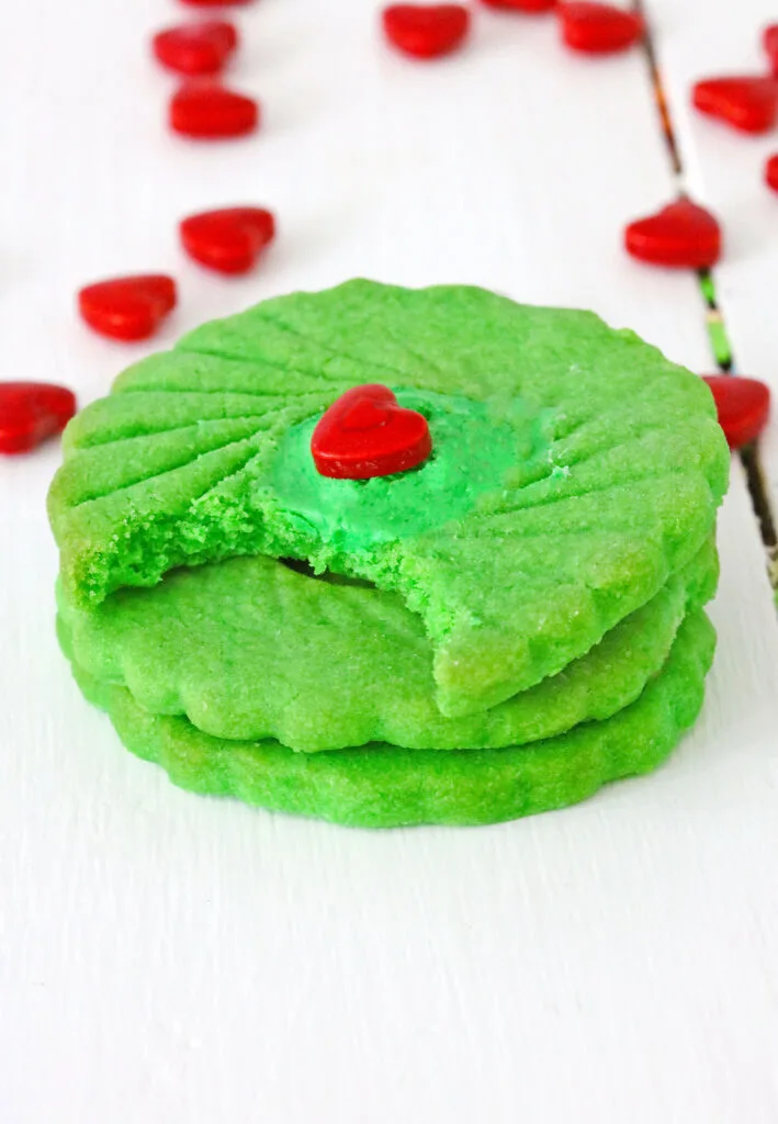 grinch thumbprint cookies stacked on white wood table