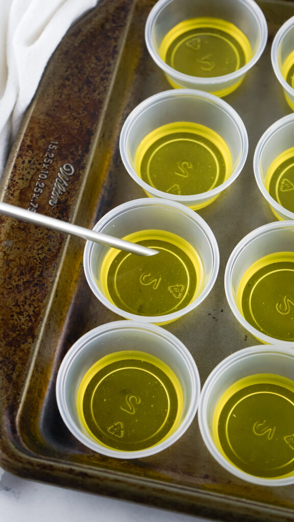 yellow jello being poured into jello shot cups